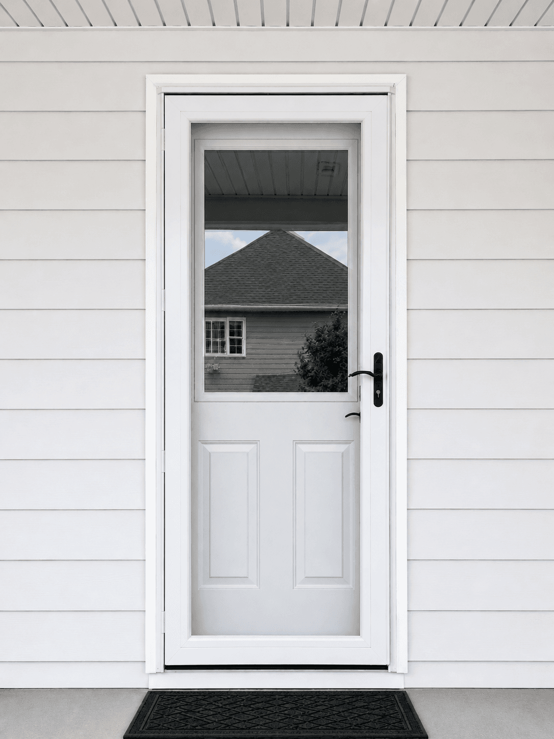 White entry door with glass window and black handle on white siding, reflecting neighboring house with dark roof